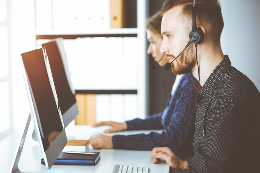 Side view of man wearing headset sitting at a computer